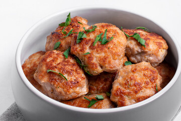 Meat cutlets with mixed mince in the ceramic bowl on the white table. Hot homemade meal