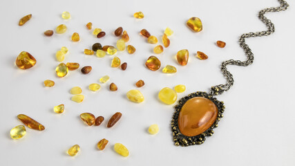 Vintage pendant made of natural Baltic amber and scattered pieces of amber on the white background....