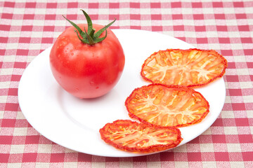 Fresh red tomato and dried tomato slices on a plate. Vitamin vegetable food