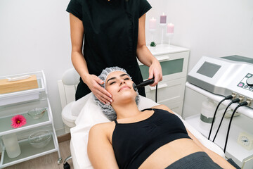 Aesthetician's short shot giving radio frequency treatment to a woman's face that rejuvenates and...