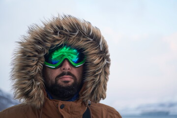 man at winter in stormy weather wearing warm fur jacket