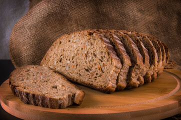 Loaf of sliced black bread, still life on a rustic background