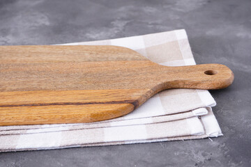 Wooden kitchen board and kitchen towel on a gray background.