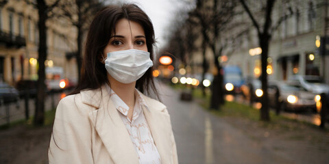Portrait of a beautiful girl in the street wearing a mask against viruses