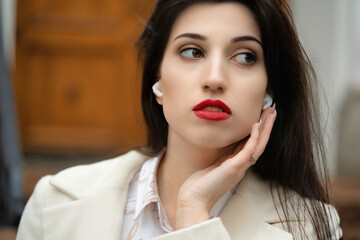 Portrait of a girl model with white headphones in her ears.