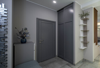 Entrance door  and wardrobe in luxury apartment. Moden interior. Grey colors. Decorative flower.