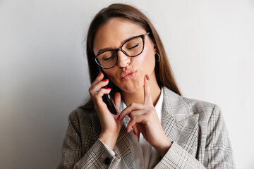 Beautiful happy businesswoman making kiss lips while talking on cellphone