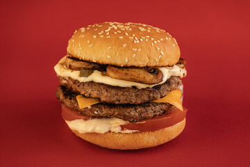 Handmade hamburger with cutlet grilled on a red background.