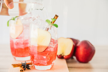 Red apple soda ice in a glass with the herb of cinnamon on wooden background.Copy space for your text