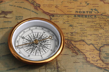 Classic round compass on old vintage map depicting North America and the United States of America as symbol of tourism with compass, travel with compass and outdoor activities with compass