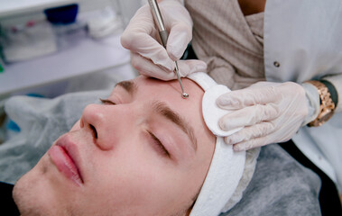 Fototapeta premium beautician makes procedures for cleansing the skin from acne