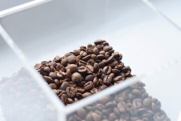 Top view on coffee beans in a transparent box on white background.