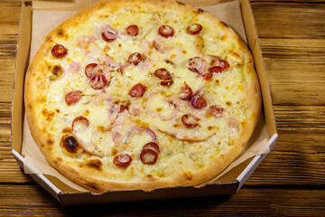 Delicious fresh pizza in cardboard box on a wooden table. Concept for home delivery of food, fast food, delivery of pizza