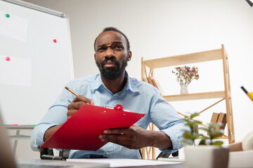 Online english courses at home. Smiling man teaches students, explaining remotely in interior of...
