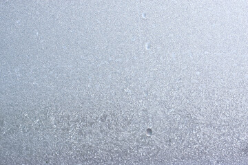 Abstract ice background, blue background with cracks on the ice surface. Frosty Christmas pattern on the winter window glass. Copy space, natural texture, macro