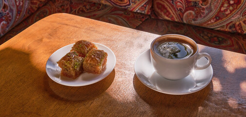 Eastern sweetness, Turkish baklava, black coffee in a white cup on a wooden table.