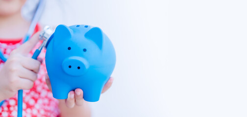 Kid girl with Stethoscope Holding blue Piggy Bank.piggy bank isolated on white background.Money...