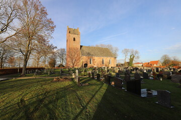 Fototapeta na wymiar On a cold but sunny day, amazing view over a traditional Dutch church with cemetery.