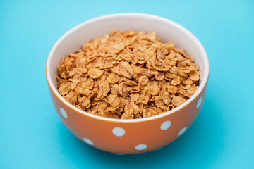 flakes wheat in the bowl on blue background