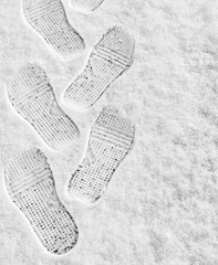 rhythmic boot prints on thin white snow in winter recede into the distance, vertical frame, ribbed protector, winter concept