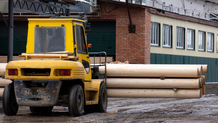 Fototapeta na wymiar The loader transports round logs at the sawmill.
