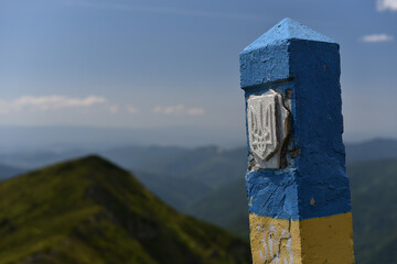 Ukrainian border line pole with coat of arms on Carpathians mountain peak on border with Romania