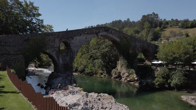 Cangas de Onis, Spain - September 4, 2020: The Roman Bridge of Cangas de On&iacute;s, the &ldquo;Puente Vieyu&rdquo; or &ldquo;Puent&oacute;n&rdquo;. Medieval stone bridge over the Sella River, Asturias, Spain.