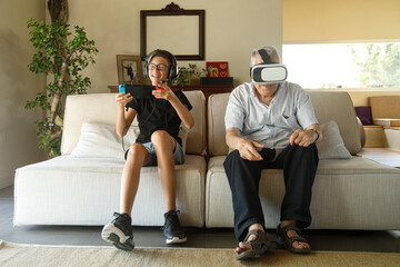 Nonno e nipote giocano con giochi elettronici seduti nel divano del salotto