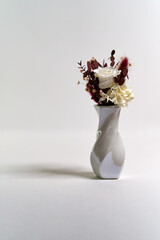 Beautiful stabilized white rose and flowers in a small vase, isolated holiday bouquet with a white background.