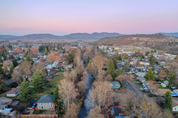 Peaceful town surrounded by trees with mountains as background