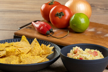 guacamole with tortillas with ingredients in the background