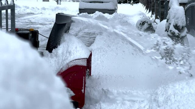 Man cleaning snow with snow blower from driveway after big snow blizzard