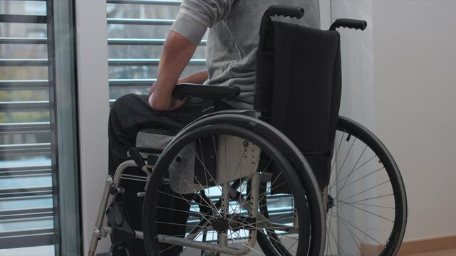Woman comforting depressed man on a wheelchair at home.