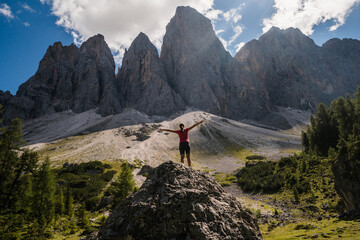 Young hiker with the back at the camera looking towards the cliffs in the Dolomites, Italy.