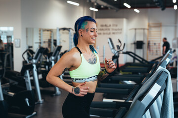 Fototapeta na wymiar tattooed young woman running on treadmill