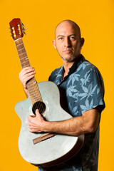 Portrait of a Musician with his blue acoustic guitar against a yellow background