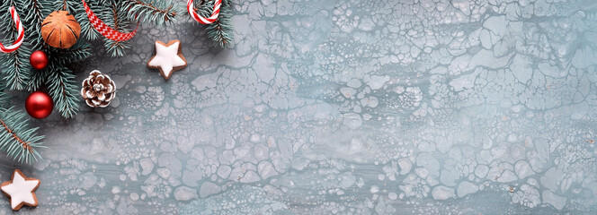 Xmas panoramic banner with copy-space. Christmas fir twigs, ribbons, cones, candy canes and wool gloves. Creative flat lay on dark textured background.