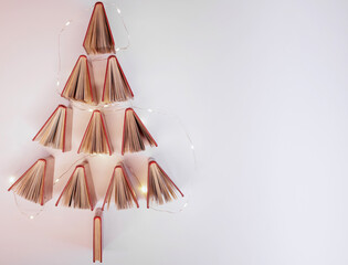 Red hard-cover books are arranged to form a Christmas tree, which it lit up with Christmas lights
