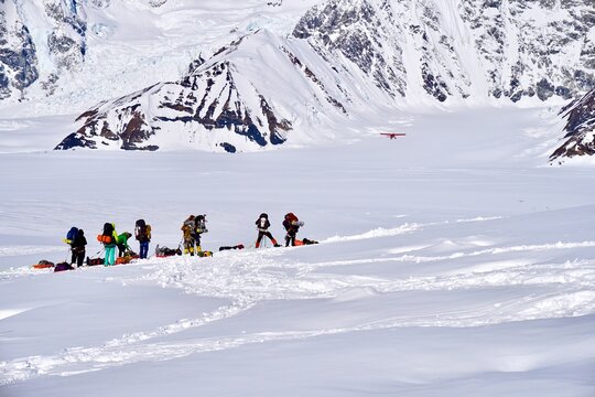 Mountain Climbers Watching A Plane Take Off From The Kahiltna Glacier