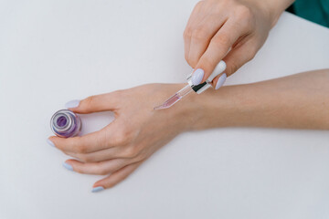 cropped view of woman applying oil from pipette on fingernails on gray background