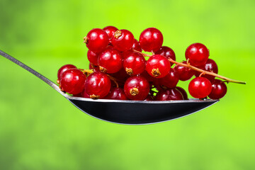 red currant in a spoon on a green background