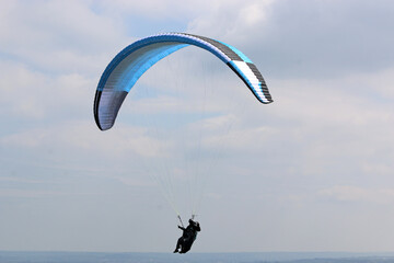 	
Paraglider flying wing in a cloudy sky	