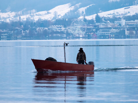 A fishing boat in the winter on the waters of the Upper Zurich Lake (Obersee), near the lakeside village of Hurden, Schwyz, Switzerland