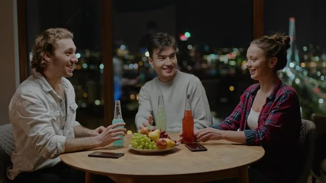 Young Company Laugh Together and Drink From Bottles