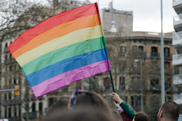 Colorful rainbow gay pride flag being waved in the breeze by a hand wearing a sweatband