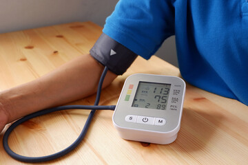 Old man checking his blood pressure and heart rate health with digital blood pressure monitor. The...