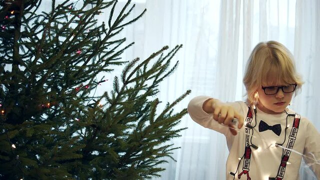 Cute boy untangling the Christmas lights. He will decorate the Christmas tree - Slow Motion