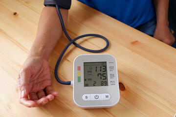 Old man checking his blood pressure and heart rate health with digital blood pressure monitor. The...