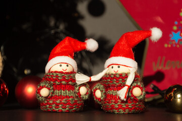couple of Christmas decorations with Christmas hats surrounded by Christmas motifs such as Christmas lights, Christmas tree, Christmas balls

