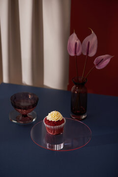 Delicious fresh red velvet cake and crystal vase with small bud of gardenia on yellow minimalistic background